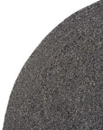 Close-up of the Armadillo&Co Braid Rug - Charcoal reveals detailed interlacing in its round, wool-blend braided design. Only a section of this handmade artisan rug appears against a white background.