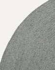 Close-up of the Armadillo&Co Braid Rug - Heron, a round, handmade wool-blend rug in grey, shown on a white background to highlight its textured surface and curved edge.