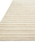 A close-up of the corner of the Cadence Rug - Beige by Loloi, featuring durable wool in beige and cream stripes with a textured, woven look against a white background.