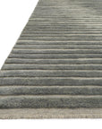 A close-up of the Loloi Cadence Rug - Grey, a durable rectangular area rug with horizontal raised stripes in gray and beige tones and fringed edges on one side.