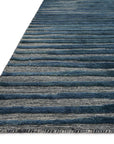 A close-up of the Loloi Cadence Rug - Navy shows horizontal blue and gray stripes and short fringe, highlighting its hand-knotted wool construction and rectangular shape.