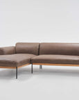 The Wooden Stories Department Modular Sofa | Leather • M1 is a modern brown leather sectional with a left-facing chaise, FSC-certified oak base, and slim black metal legs, shown against a plain white background.