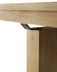 Close-up of an Ethnicraft Double Extendable Dining Table - Oak, highlighting the solid oak tabletop edge, sturdy wooden leg, and black metal bracket securing the leg for a stylish and durable dining solution.