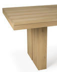 A close-up of the Ethnicraft Double Extendable Dining Table – Oak, showcasing its light natural finish, thick rectangular top, sturdy wide legs, and sleek angular lines.