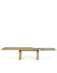 The Ethnicraft Double Extendable Dining Table - Oak is shown with one end extended, displaying its sliding mechanism and extra leaf for added length, set against a white background.