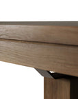 Close-up of the Ethnicraft Double Extendable Dining Table in natural teak, highlighting its detailed wood grain, thick tabletop, and sturdy leg with a metal bracket joining the leg and tabletop.
