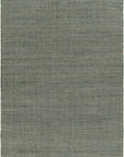 The Surya Evora Rug is a rectangular, flat-woven 100% jute rug made in India, featuring a muted grayish-blue tone and minimal pattern with a subtly uneven texture.