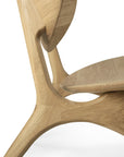 Close-up of the Ethnicraft Eye Lounge Chair - Oak, featuring smooth curved lines and European oak grain. The image highlights the chair’s sleek design, focusing on its seat, backrest, and detailed leg joint craftsmanship.