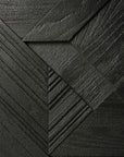Close-up of the Ethnicraft Graphic Sideboard - 4 door: textured solid black teak panels arranged in overlapping diagonal and triangular patterns create a visually striking, contract grade geometric effect.