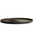 The Ethnicraft Graphite Combined Dots Glass Tray—Round / Extra Large—features a low rim and reflective tinted surface, offering European refinement against a plain white background.