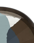 A close-up of the Ethnicraft Graphite Wabi Sabi Glass Tray—Round / Extra Large—shows its dark wooden rim and organic shapes in muted hues like light blue, brown, dark blue, and gray, echoing modern art with European sophistication.