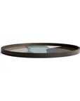 The Ethnicraft Graphite Wabi Sabi Glass Tray (Round / Extra Large) features raised edges and an abstract, multicolored organic pattern in muted blues, greens, grays, and browns for a touch of European sophistication.