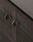 Close-up of two round, metallic knobs on the textured black-stained teak doors of the Ethnicraft Grooves Sideboard – 4 Door, highlighting European refinement and a smooth, dark top surface.
