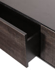 A close-up of the Grooves TV Cupboard - 95 by Ethnicraft showcases its dark wooden drawer with a ribbed front, smooth, modern design, and black metal legs, with the rest of this elegant furniture piece visible in the background.