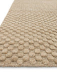 A close-up of the Loloi Hadley Rug - Dune shows its beige, loom-knotted, hand-cut pile with a raised dot pattern. A corner of the textured rug from the Hadley Collection appears against a white background.