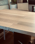 A close-up of the SOBU Hinge Extension Dining Table in white oak highlights the seam where its sections meet, with chairs and decor visible in the background.