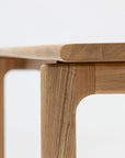 Close-up of the Hover Dining Table | Light Oak by Wooden Stories, highlighting its smooth, rounded corner, minimalist Danish design, and light oak grain against a plain white background.