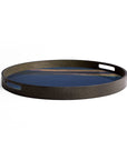 The Indigo Organic Glass Tray by Ethnicraft is a small, round serving tray with side handles. Its dark wood base displays organic blue and brown forms, evoking water and land, from the Tray Collection. Background is plain white.