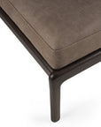 Close-up of the Ethnicraft Jack Footstool in nubuck leather, showcasing its brown cushion and dark wooden frame, with Scandinavian modernism details at the seat corner and leg.
