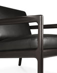 Close-up of the Ethnicraft Jack Lounge Chair in black leather, inspired by Scandinavian modernism and featuring a dark wooden frame, set against a white background.
