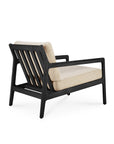 The Jack Outdoor Lounge Chair by Ethnicraft features an FSC certified black teak frame and natural outdoor-grade cushions. Its modern design includes clean lines and a slatted backrest, shown here from the rear angle.