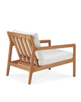 The Jack Outdoor Lounge Chair by Ethnicraft features angled legs, an open slatted teak back, and a light off-white cushioned seat. Its minimalist modern design makes it perfect for contemporary outdoor spaces.
