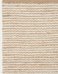 A close-up of the Armadillo&Co Kalahari Rug - Natural / Chalk shows handwoven jute with alternating beige and off-white stripes, creating a textured, simple look and a finished edge.