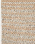 A close-up of the Armadillo&Co Kalahari Rug in Natural / Pumice shows its braided handwoven jute texture in beige, tan, and light gray, with the rug’s edge visible at the top.