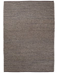 The Kalahari Weave Rug - Pewter / Charcoal by Armadillo&Co is a rectangular handwoven jute rug featuring a subtle zigzag pattern in pewter and charcoal, with a textured look and dark borders on the top and bottom edges.