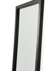 A close-up of the Ethnicraft Light Frame Floor Mirror - Black, featuring a thick black-stained oak frame, leaning slightly backward against a white background.