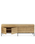 The Ethnicraft Ligna Sideboard features four drawers above four cabinet doors, crafted from European oak with a natural finish and black metal legs; two doors are open to show the empty shelves inside.