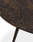 Close-up of the Ethnicraft Luna Coffee Table - Whiskey, featuring a round, dark, textured surface with subtle marbling, expertly crafted and supported by slender black legs against a plain white background.