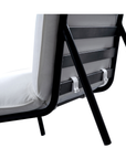 Close-up of the back and legs of the Moes Morgan Outdoor Chair, showcasing its black stainless-steel frame, light Olefin fabric cushion with a securing strap, all set against a plain white background.