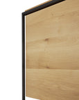 Close-up of a solid oak panel with natural grain, bordered by slim black metal—featured on the Monolit Sideboard - 2 door by Ethnicraft.