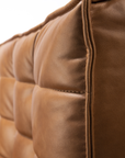 Close-up of a brown, tufted cushion from the Ethnicraft N701 Sectional Sofa - Old Saddle, featuring genuine full aniline leather. Visible stitching and a quilted, padded surface showcase its rich texture and quality craftsmanship.