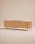 The Nell Sideboard | Light Oak by Wooden Stories features a long, minimalist Scandinavian design with four cabinet doors, crafted from solid oak and photographed against a neutral beige background.