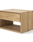 The Ethnicraft Nordic II Bedside Table is crafted from solid European oak and features a single drawer, open shelf, and a natural light finish in a simple, modern design.