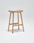 The Odd Counter Stool by Wooden Stories features a light oak frame, a genuine leather seat, and four sturdy legs, showcased against a plain white background.