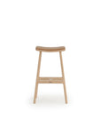 The Odd Counter Stool by Wooden Stories features a light oak frame with a leather seat. Its curved design and clean lines reflect Danish minimalism, while premium natural materials ensure both elegance and comfort. Shown on a white background.