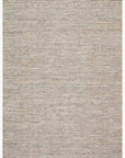 The Omen Rug - Grey by Loloi is a hand-woven rectangular area rug featuring subtle chevron waves in light beige and gray, finished with short fringe on the top and bottom edges.