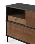 A close-up of the Ethnicraft Oscar Sideboard, featuring a dark top, ribbed sliding doors, black legs, and an open shelf with a light wood drawer and round cut-out handle—an example of timeless Ethnicraft design.