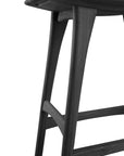 A close-up of the Ethnicraft Osso Barstool - Black shows its black stained solid oak, angled legs, rounded edges, and footrests, all set against a white background.