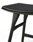 Close-up of Ethnicraft’s Osso Dining Stool in black, showcasing a padded black leather seat, smooth curved edges, and sturdy angled legs—offering modern European refinement against a plain white background.