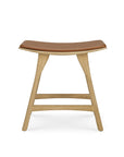 The Ethnicraft Osso Dining Stool features European styling with curved solid oak legs and a light brown leather seat, shown against a white background.