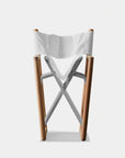 The Harbour Pacific Folding Chair - Teak features a solid teak frame, white canvas seat and backrest, and silver metal supports, shown here against a plain white background.