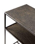 A close-up side view of the Ethnicraft Pentagon Console - Whiskey shows its modern metal frame and textured, cracked dark brown surface with natural pigments, set against a white background.