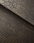 Close-up of Ethnicraft’s Pentagon Nesting Coffee Tables - Whiskey: the top half shows a cracked, dry earth texture reminiscent of natural mineral powders, while the bottom displays horizontal ridges—both in dark, earthy, European-inspired tones.
