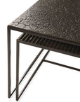 The Ethnicraft Pentagon Nesting Coffee Tables in Whiskey showcase European refinement with thin black metal frames, a textured top table crafted from natural mineral powders, and a grooved lower table, shown from an overhead angle.