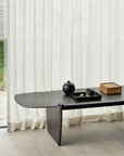 The Ethnicraft PI Coffee Table - Mahogany is styled with a black tray, teapot, cup, and wooden box on light wood flooring in front of sheer white curtains and a large window.