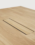 A close-up of the Ethnicraft Geometric Meeting Table - Oak shows its integrated rectangular wire management cutout, seamlessly blending with the solid oak surface, set against a white background.